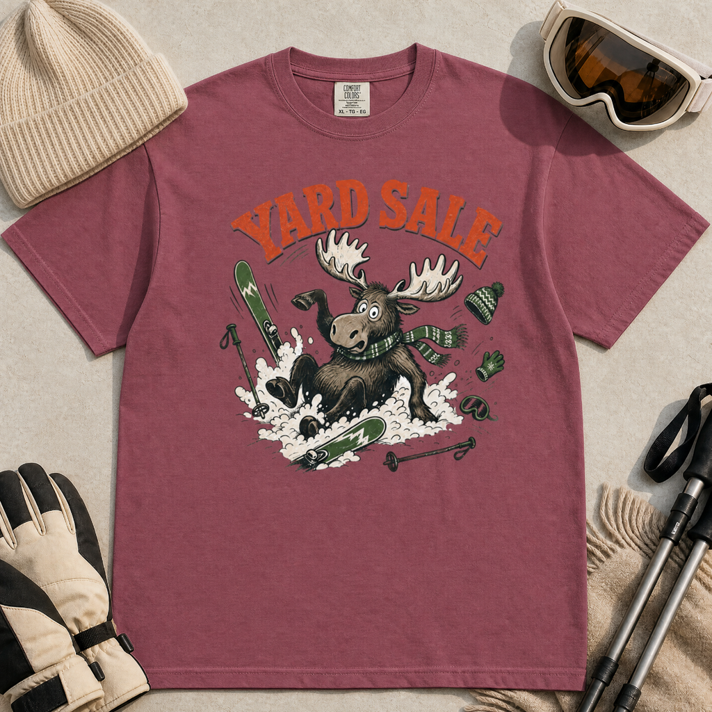 Brick red t-shirt with moose graphic and 'Yard Sale' text, surrounded by winter accessories on a light background