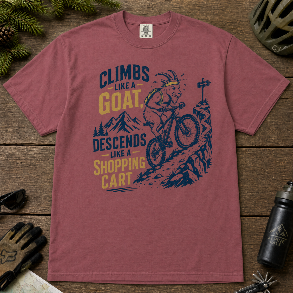Brick red t-shirt with mountain bike graphic and text on a wooden surface with cycling accessories.
