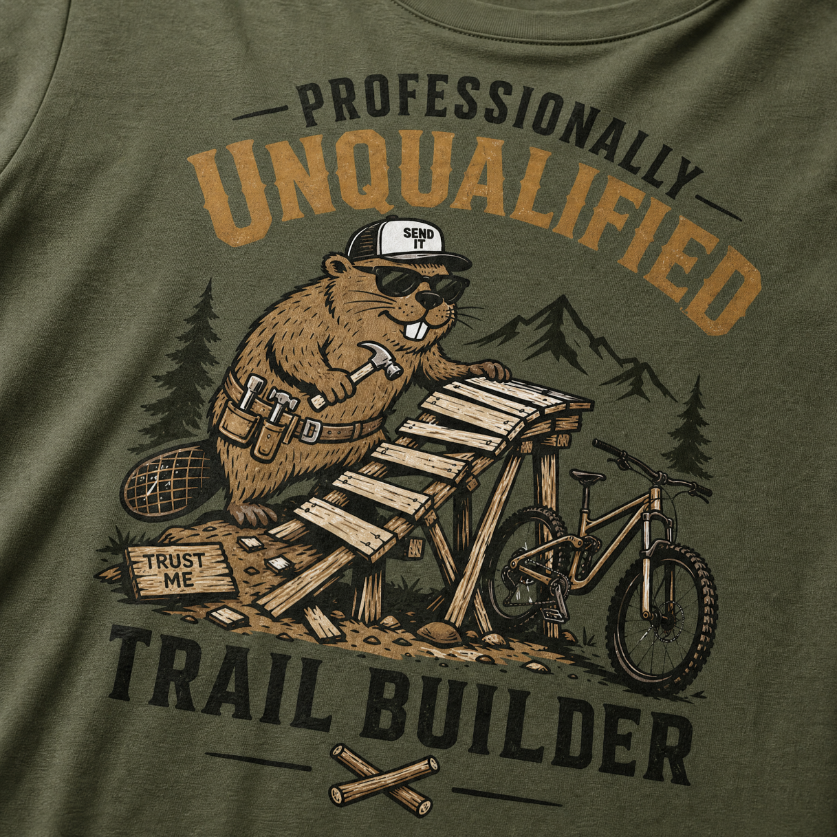 Hemp green t-shirt with a beaver graphic and text 'Professionally Unqualified Trail Builder' on a mountainous background.