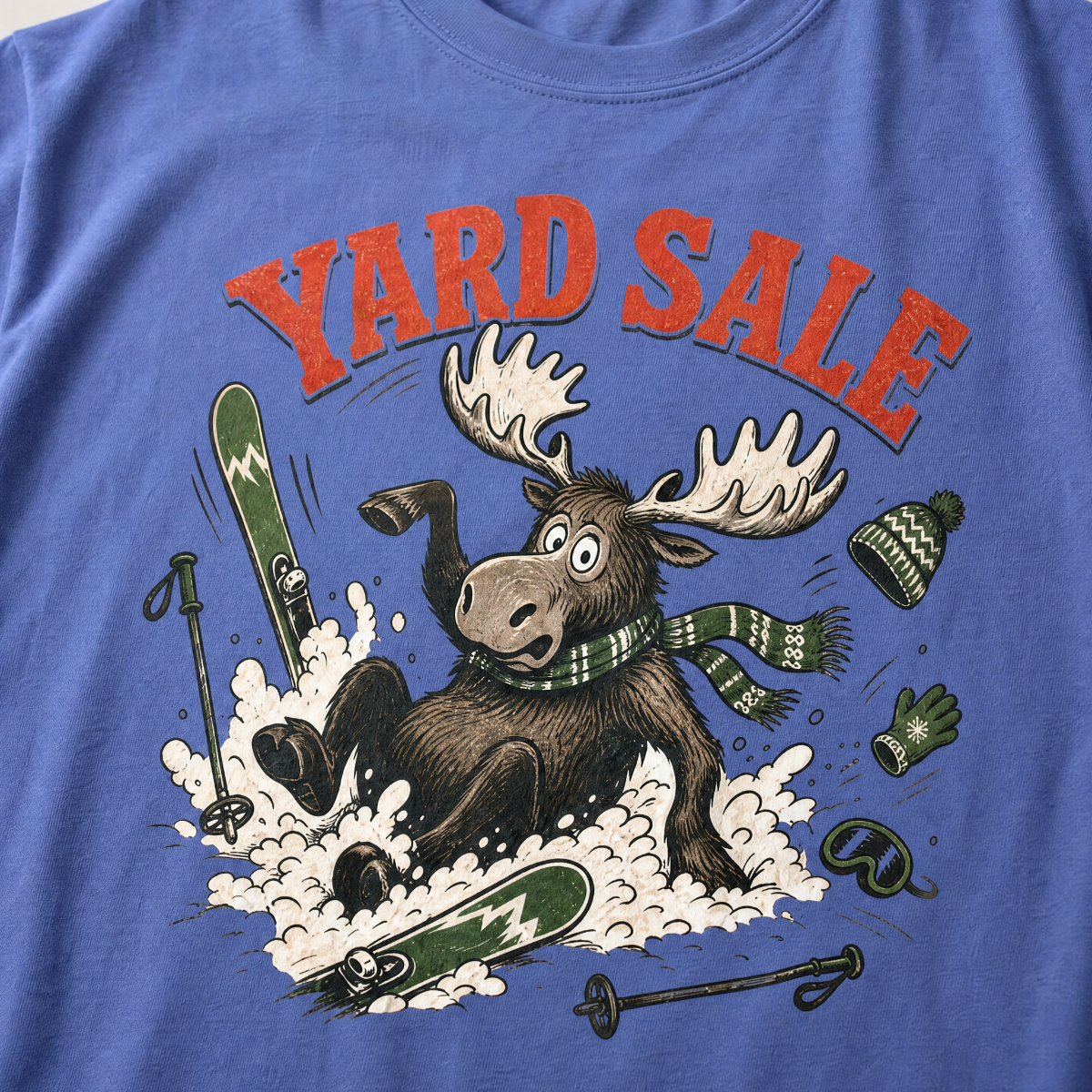 Mystic blue t-shirt with moose graphic and 'Yard Sale' text, surrounded by winter accessories on a light background