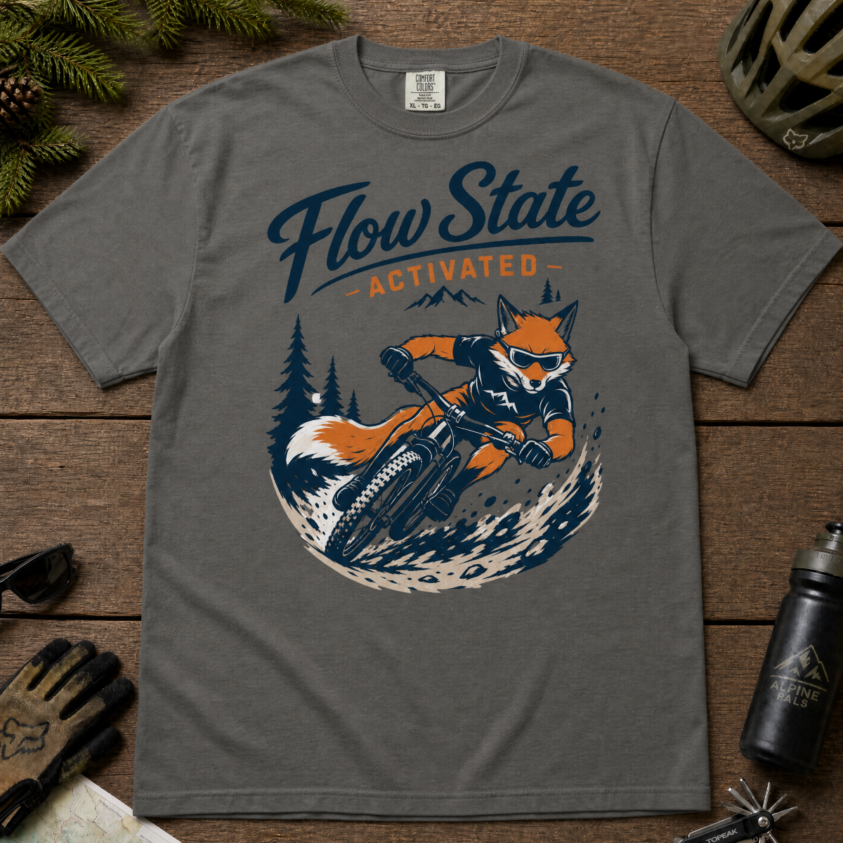 Pepper gray t-shirt with a fox riding a bike graphic and 'Flow State Activated' text on a wooden surface.