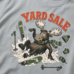 Granite gray t-shirt with moose graphic and 'Yard Sale' text, surrounded by winter accessories on a light background