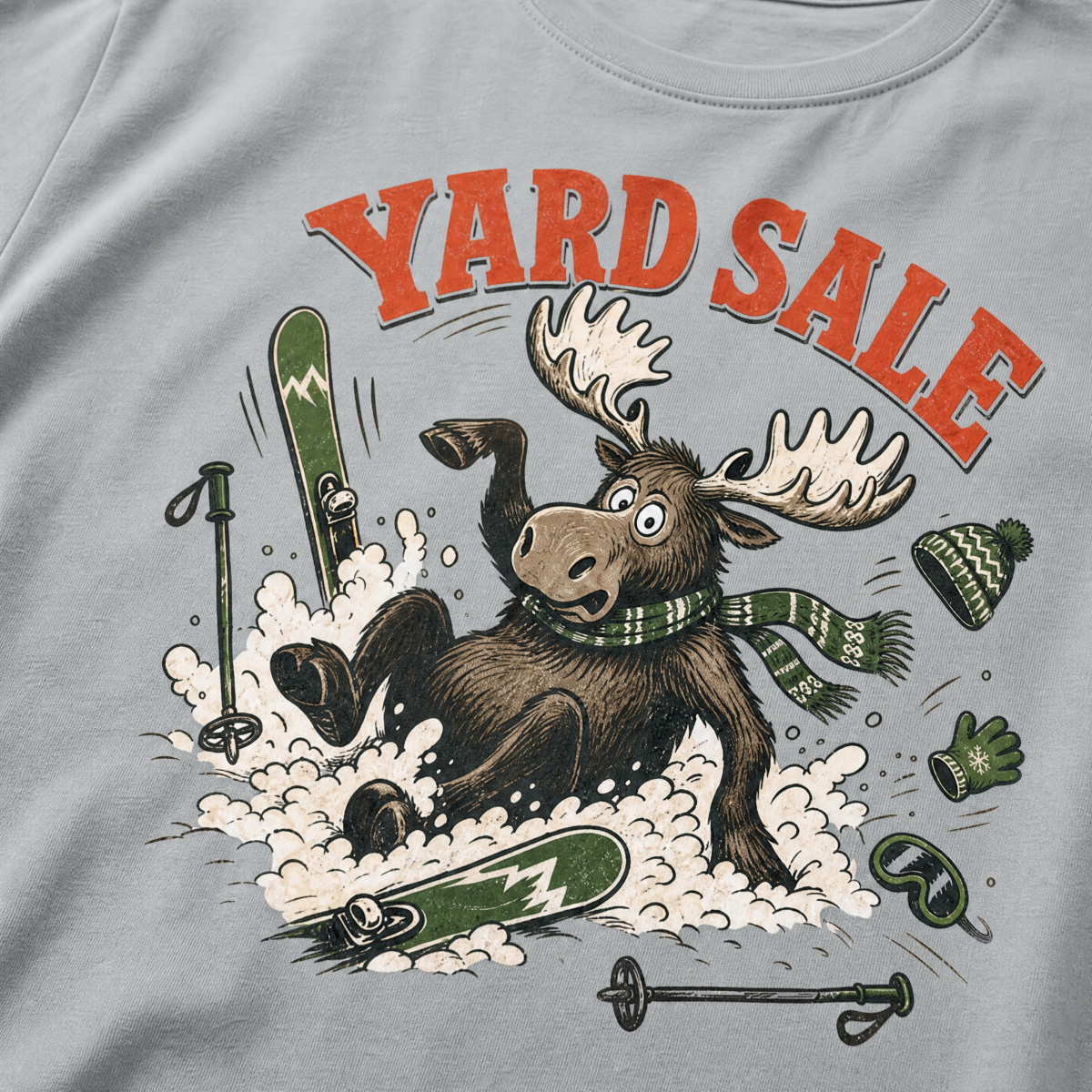 Granite gray t-shirt with moose graphic and 'Yard Sale' text, surrounded by winter accessories on a light background