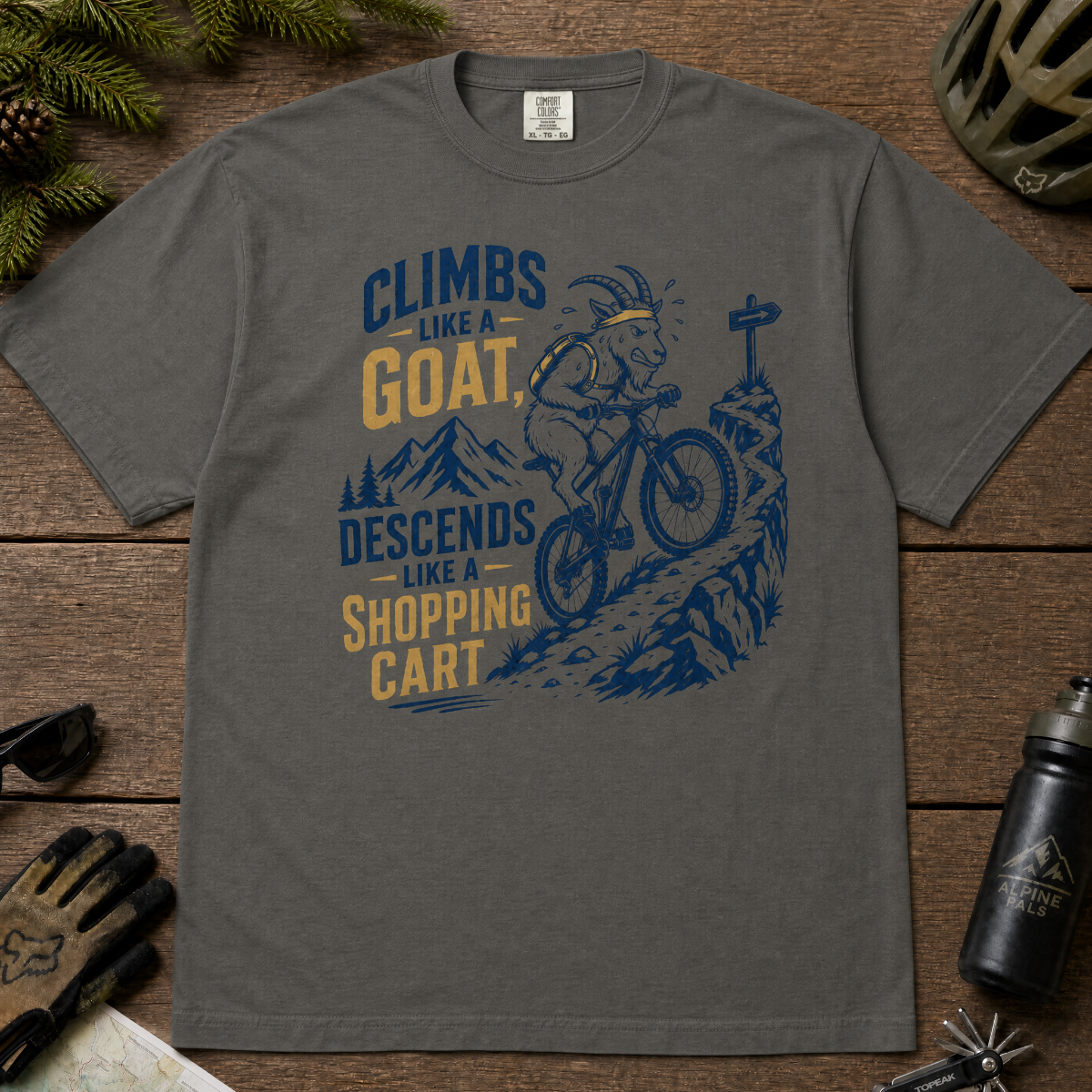 Pepper gray t-shirt with graphic design and text on a wooden surface with outdoor gear.
