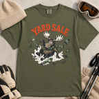 Hemp green t-shirt with moose graphic and 'Yard Sale' text, surrounded by winter accessories on a light background