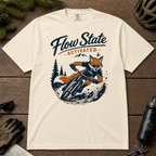 Ivory white t-shirt with a fox riding a bike graphic and 'Flow State Activated' text on a wooden surface.
