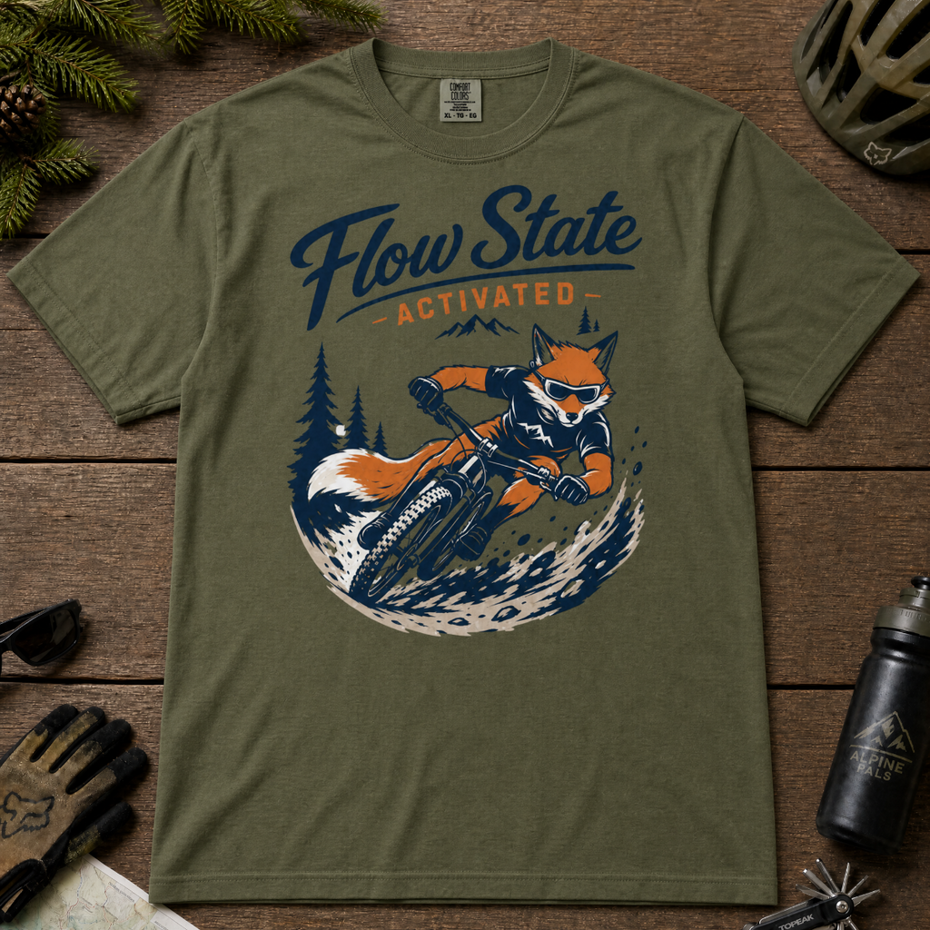 Hemp green t-shirt with a fox riding a bike graphic and 'Flow State Activated' text on a wooden surface.