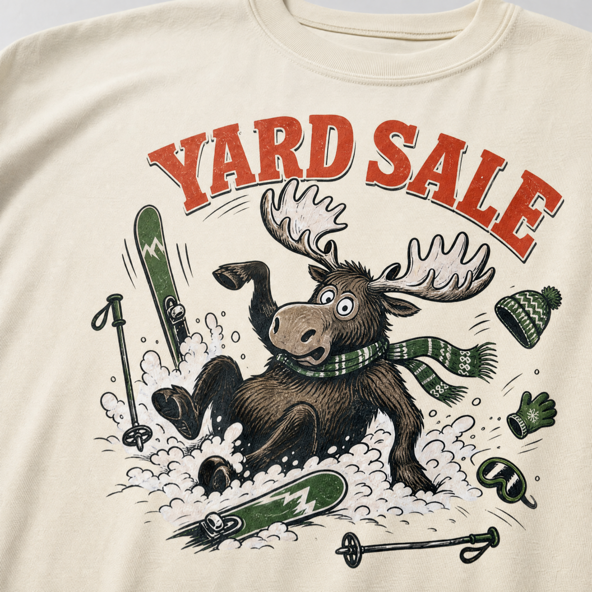 Ivory white t-shirt with moose graphic and 'Yard Sale' text, surrounded by winter accessories on a light background