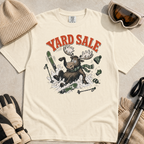 Ivory white t-shirt with moose graphic and 'Yard Sale' text, surrounded by winter accessories on a light background