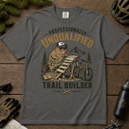 Pepper gray t-shirt with graphic design of a beaver building a trail, surrounded by outdoor gear on a wooden surface.