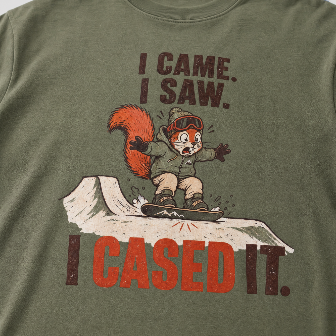 Moss green t-shirt with a graphic of a squirrel on skis and text 'I Came. I Saw. I Cased It.'