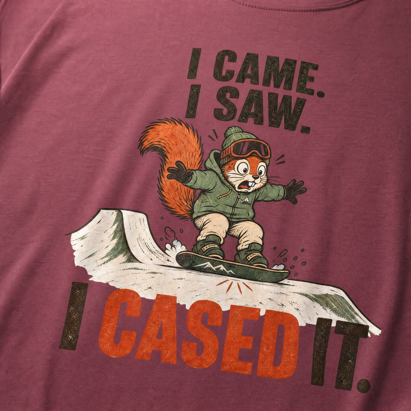 Brick red t-shirt with a graphic of a squirrel on a snowboard and humorous text.