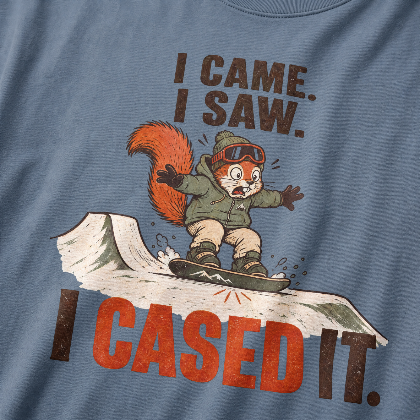 Blue jean colored t-shirt with a cartoon squirrel on a snowboard and humorous text.