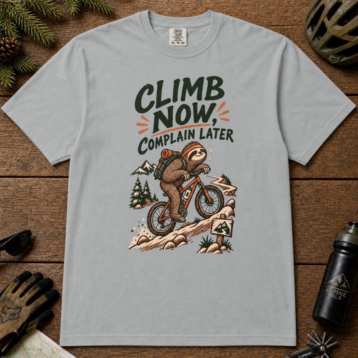 Granite t-shirt featuring a sloth mountain biking uphill beneath the phrase “Climb Now, Complain Later.”