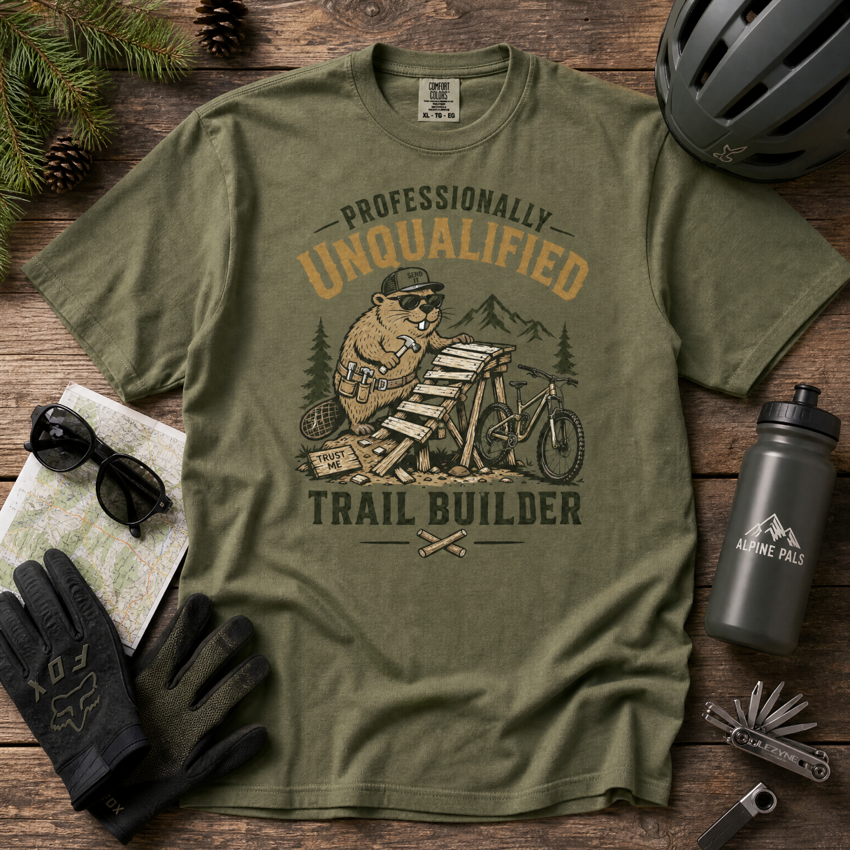 Green t-shirt with beaver graphic and text on a wooden surface with accessories.