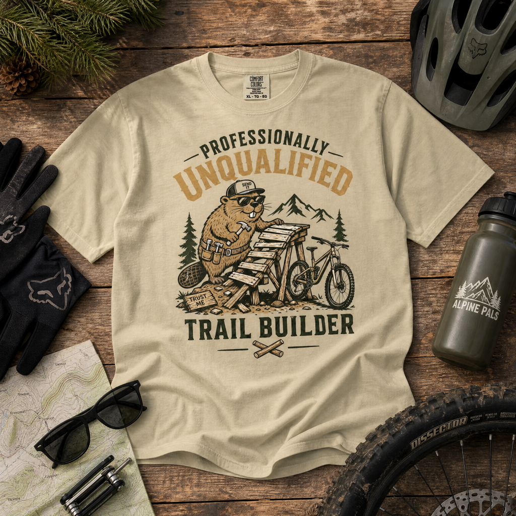 Beige t-shirt with bear graphic and text on a wooden surface with outdoor gear.