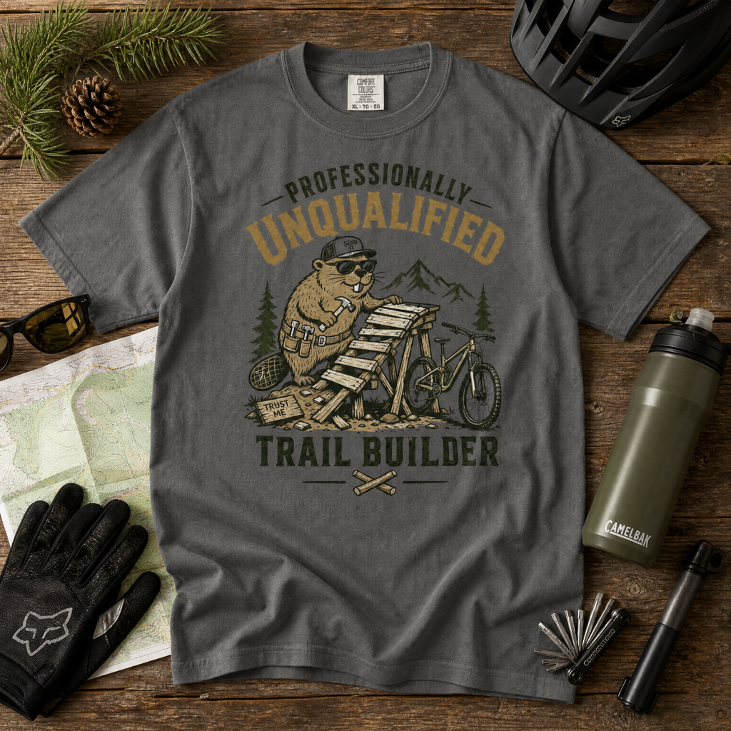 Gray t-shirt with a beaver graphic and text on a wooden surface with outdoor gear.