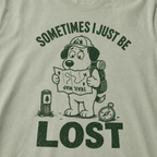 Close-up of a bay green t-shirt with a green “Sometimes I Just Be Lost” trail design showing a confused dog reading an upside-down map.
