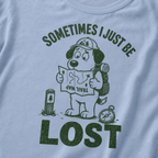 Close-up of a WASHED DENIM BLUE t-shirt with a green “Sometimes I Just Be Lost” trail design showing a confused dog reading an upside-down map.