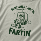 Close-up of a bay green t-shirt with a playful frog chairlift graphic and bold “Sometimes I Just Be Fartin’” text.