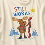 Close-up of an ivory white t-shirt with a playful crayon-style ski design showing a smiling moose holding a red ski, with “Still Works.” text.