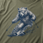 Close-up of a moss green t-shirt with a dynamic bear skier graphic showing the bear carving through snow with goggles and ski poles.