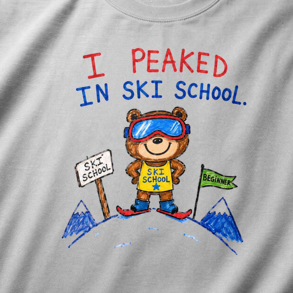 Close-up of a granite gray t-shirt with a playful hand-drawn bear at ski school, beginner flag, mountain details, and “I Peaked in Ski School.” text.