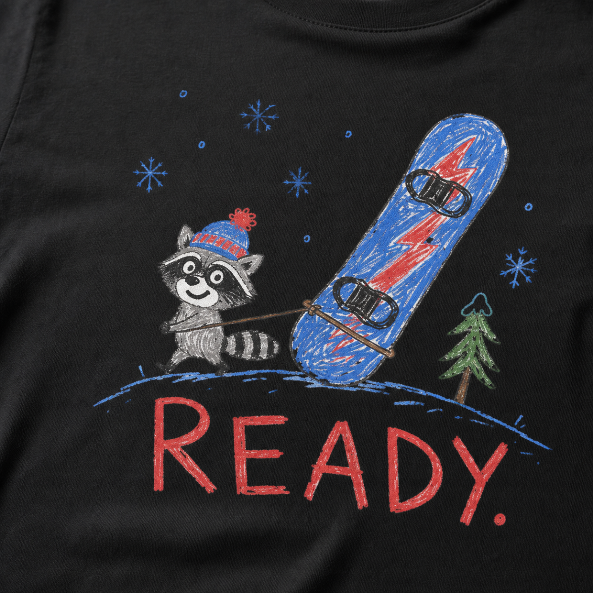 Close-up of a black t-shirt with a playful hand-drawn raccoon snowboarding graphic, snowflakes, a pine tree, and large red “READY.” text.