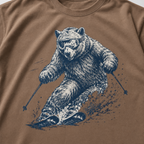 Close-up of an espresso brown t-shirt with a dynamic bear skier graphic showing the bear carving through snow with goggles and ski poles.