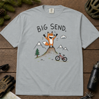Flat lay of a granite gray t-shirt featuring a playful hand-drawn fox mountain bike graphic with mountains, a small bike, and “Big Send.” text.