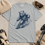 Flat lay of a granite gray t-shirt featuring a detailed blue line-art bear skiing through powder, styled with winter accessories.