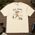 Flat lay of an ivory white t-shirt featuring a playful hand-drawn fox mountain bike graphic with mountains, a small bike, and “Big Send.” text.
