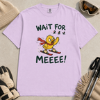 Flat lay of an orchid t-shirt featuring a panicked duck skiing behind the group with a red scarf and “Wait for Meeee!” text.