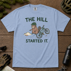 Flat lay of a washed denim blue t-shirt with a humorous mountain biking design showing an annoyed beaver blaming a dirt hill beside its bike.