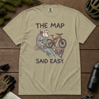 Flat lay of a khaki t-shirt with a humorous mountain biking design showing a nervous opossum, an orange bike, and a dangerously steep trail.