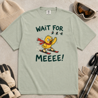 Flat lay of a bay green t-shirt featuring a panicked duck skiing behind the group with a red scarf and “Wait for Meeee!” text.