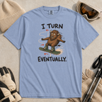 Flat lay of a washed denim blue t-shirt featuring a nervous bison snowboarding along a winding path with “I Turn Eventually.” text.