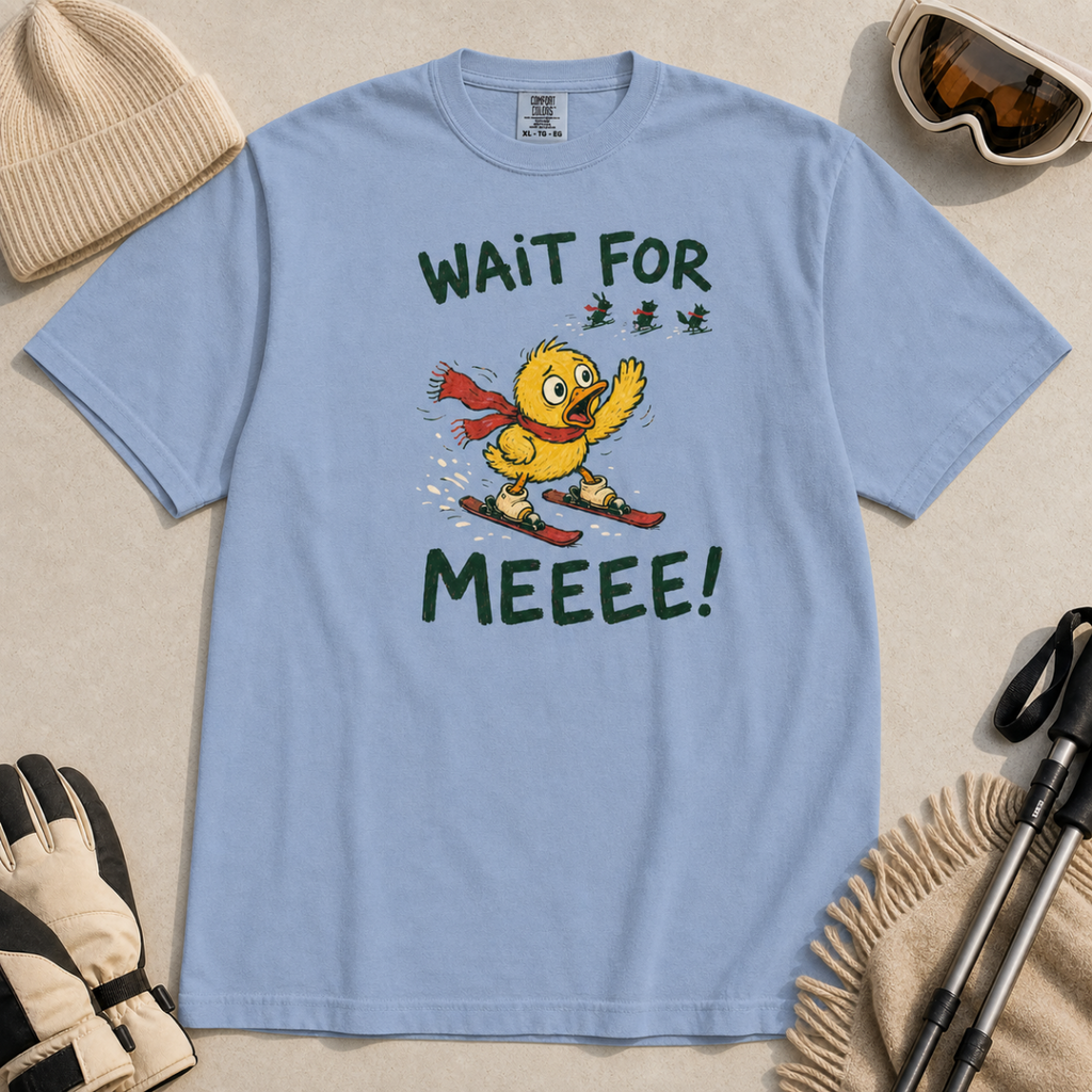 Flat lay of a washed denim blue t-shirt featuring a panicked duck skiing behind the group with a red scarf and “Wait for Meeee!” text.