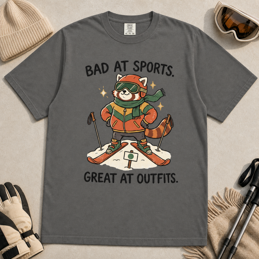 Flat lay of a pepper gray t-shirt with a humorous red panda ski design celebrating fashionable gear over athletic ability.