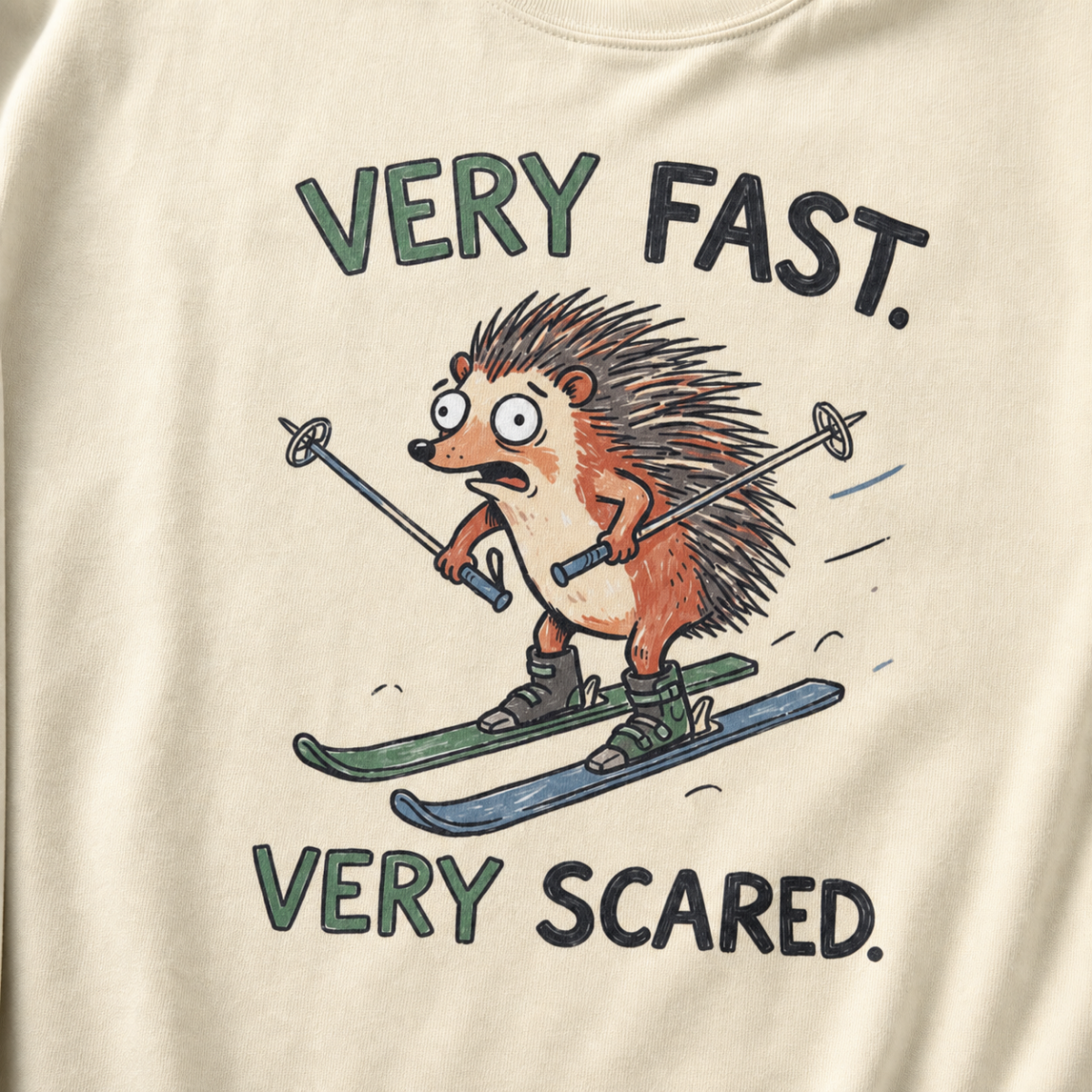 Close-up of an ivory white t-shirt with a playful hedgehog ski graphic showing the wide-eyed animal racing downhill with poles and mismatched skis.