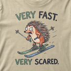 Close-up of a khaki t-shirt with a playful hedgehog ski graphic showing the wide-eyed animal racing downhill with poles and mismatched skis.