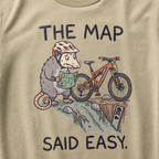 Close-up of a khaki t-shirt featuring a worried opossum checking an “easy” trail map beside a mountain bike at a steep drop, with “The Map Said Easy.” text.