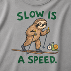 Close-up of a grey t-shirt featuring a relaxed sloth cross-country skiing beside a snail with a stopwatch and “Slow Is a Speed.” text.