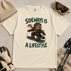 Flat lay of an ivory white t-shirt with a playful wolverine snowboard graphic and bold “Sideways Is a Lifestyle” text.
