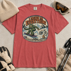 Crimson red t-shirt featuring a vintage backcountry badge design with Bigfoot snowboarding, a mountain bike, snowy peaks, and “I Packed for Everything” lettering.