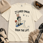 Flat lay of an ivory white t-shirt with a humorous snowboarding design showing a worried rabbit facing an unexpectedly steep jump.