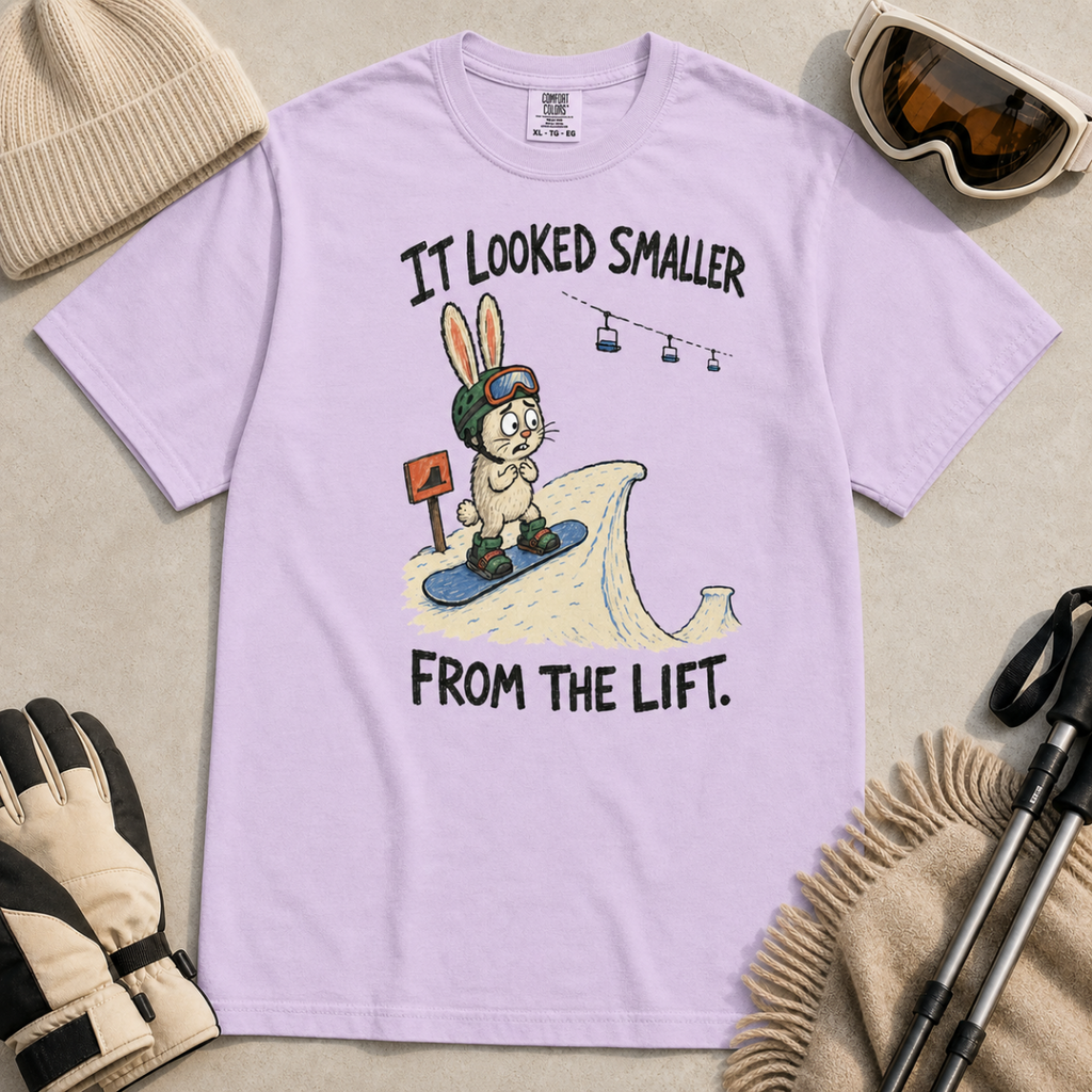 Flat lay of an orchid t-shirt with a humorous snowboarding design showing a worried rabbit facing an unexpectedly steep jump.