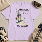 Flat lay of an orchid t-shirt with a humorous snowboarding design showing a worried rabbit facing an unexpectedly steep jump.