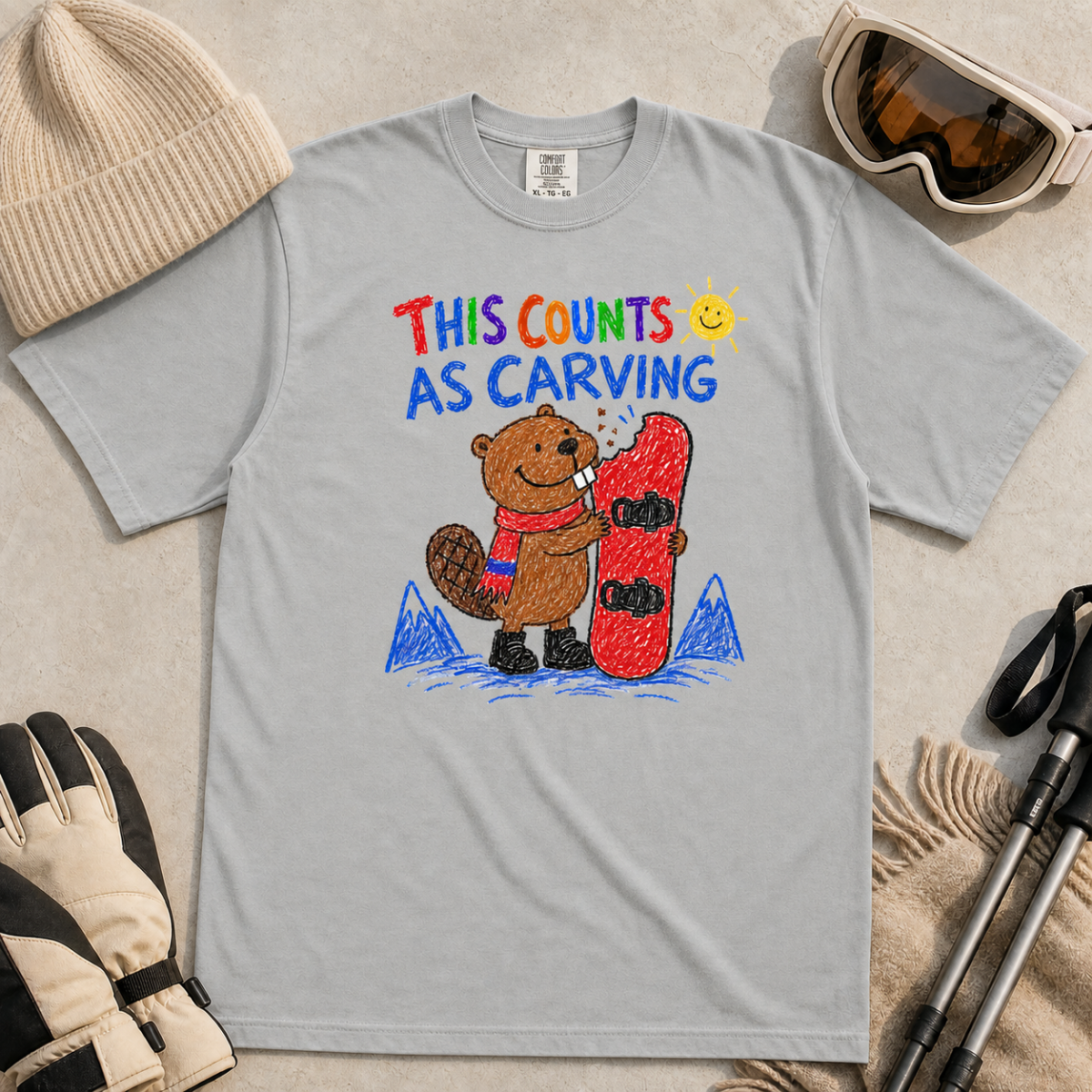 Flat lay of a granite gray t-shirt with a playful beaver snowboarding design showing the animal chewing a board beneath “This Counts as Carving” text.