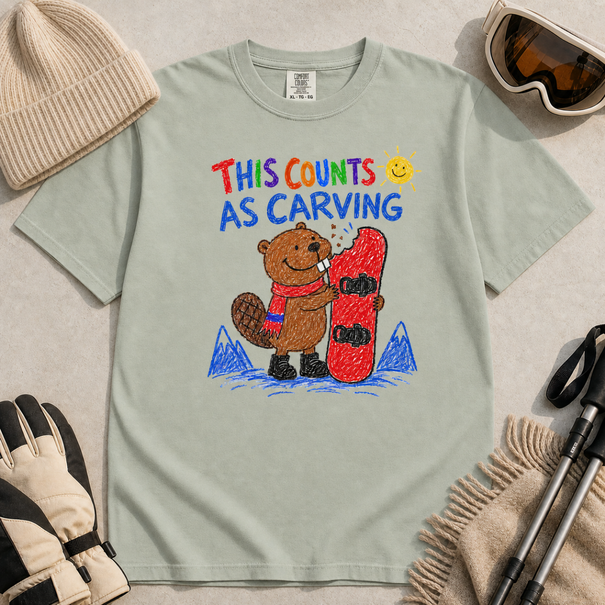 Flat lay of a bay green t-shirt with a playful beaver snowboarding design showing the animal chewing a board beneath “This Counts as Carving” text.